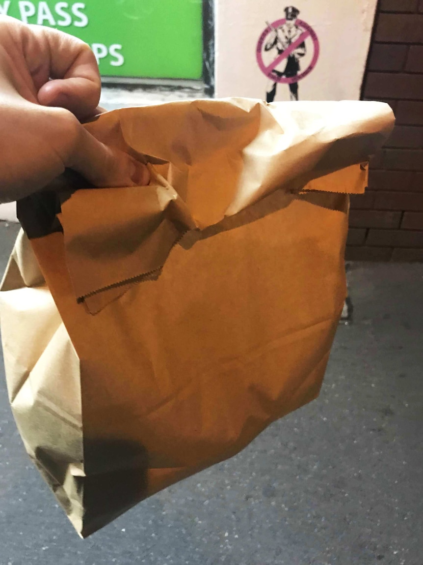 A man holds a brown paper bag representing our reporter's attempt to go one week without plastic.