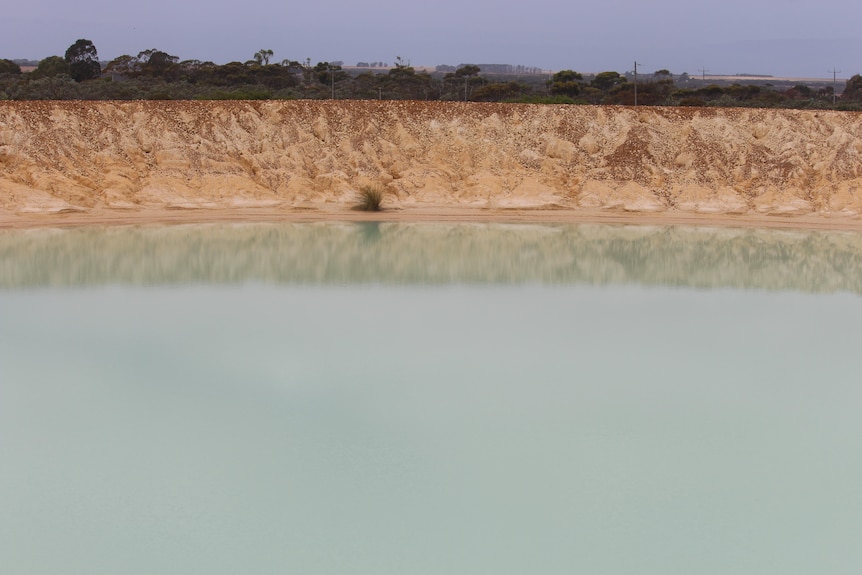 The dam is still, reflective and milky-green