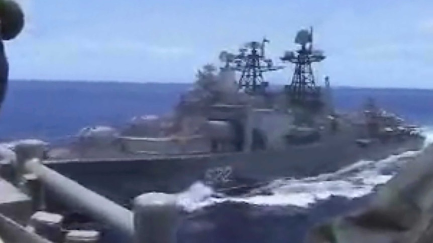 Blurry close up image of a Russian destroyer coming very close to a US warship