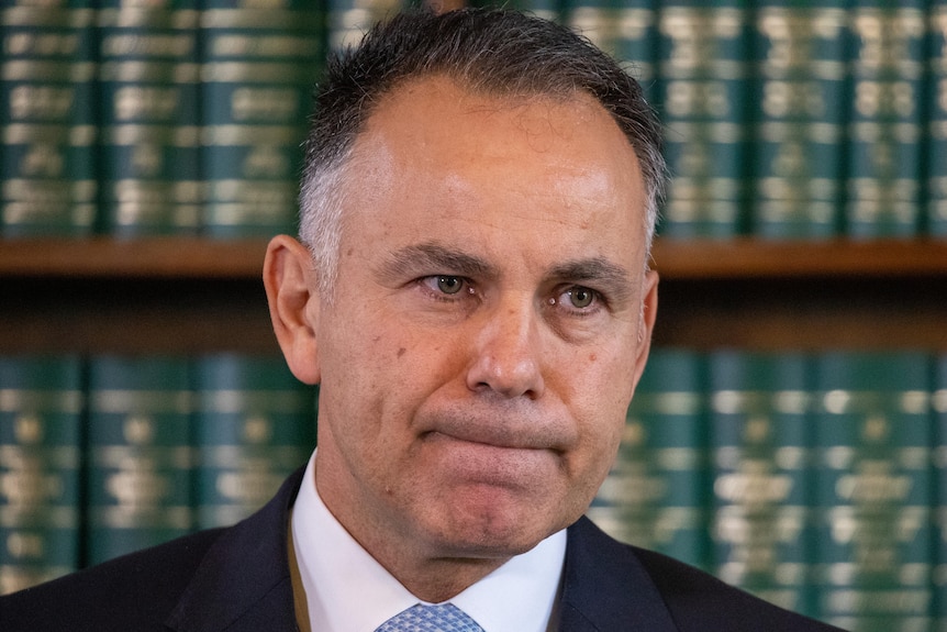 John Pesutto appears serious, standing inside Parliament in front of a bookshelf.