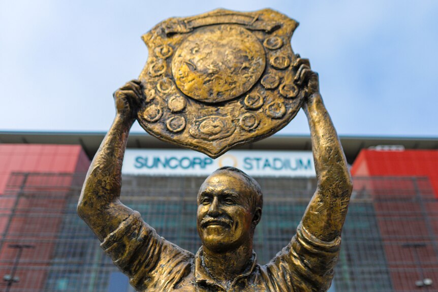 A close-up of the Wally Lewis statue outside Lang Park, with the Suncorp Stadium sign in the background.