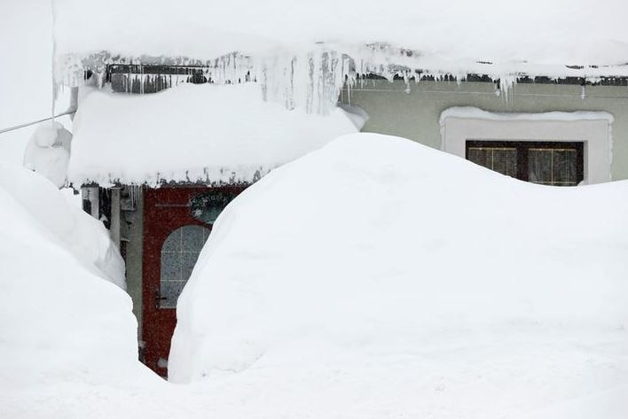 A front for of a house covered in snow is partially seen.