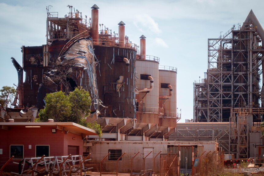 A decrepit and falling apart alumina refinery which has been stained a reddish colour