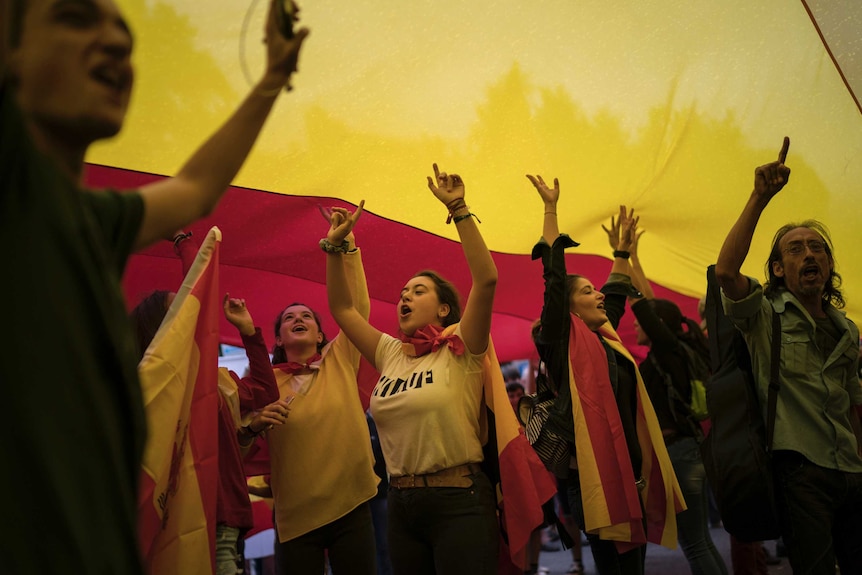 Demonstrators display a giant Spanish flag over their heads while marching against the referendum.