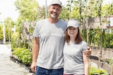 a tall man and a smaller woman smile while standing in a nursery.