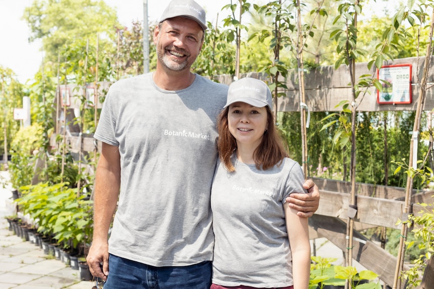 a tall man and a smaller woman smile while standing in a nursery