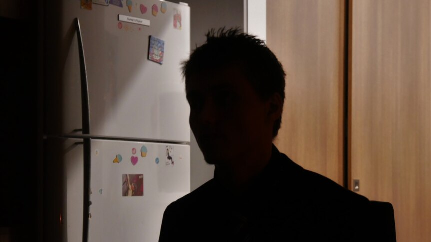 The silhouetted profile of a youth/man in a kitchen