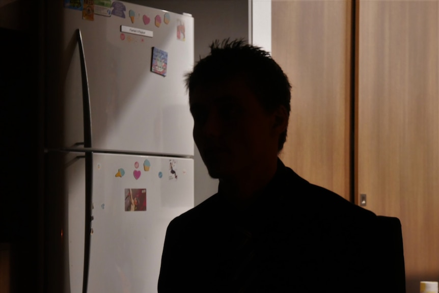 The silhouetted profile of a youth/man in a kitchen