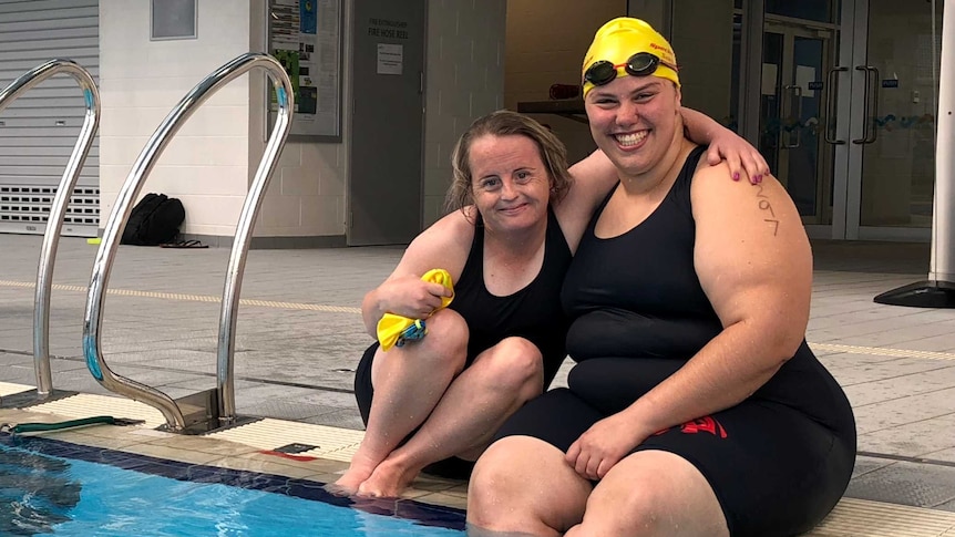 Swimmers Danah Gobbett and Tryphena Nicolai sit together by the pool.