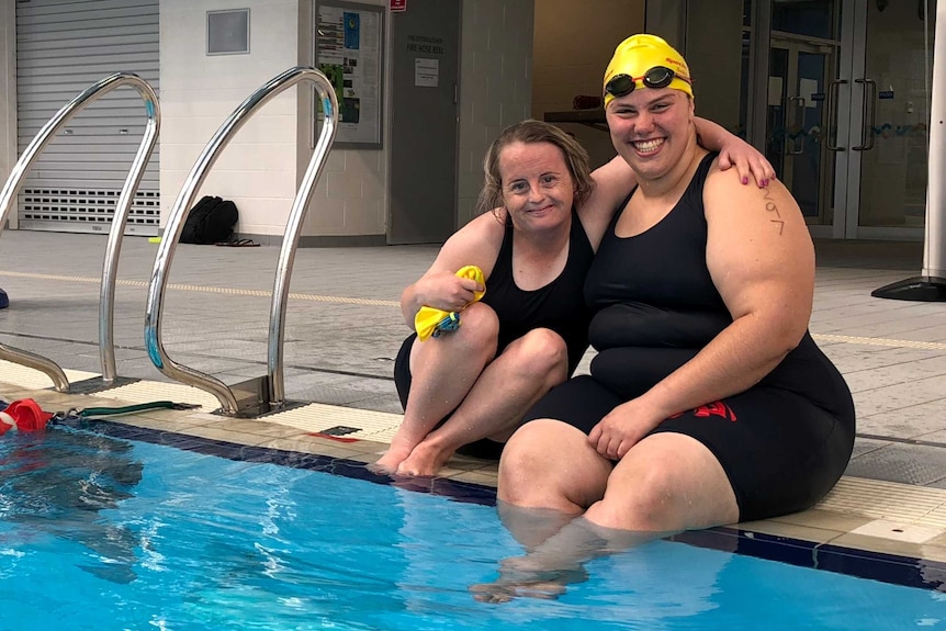 Swimmers Danah Gobbett and Tryphena Nicolai sit together by the pool.
