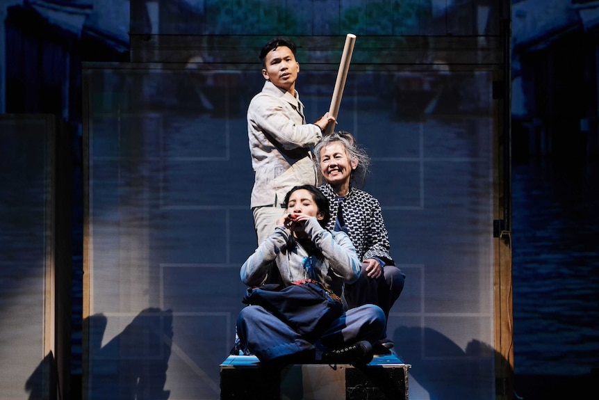 A young east asian man rows a boat with an older east asian woman and a younger east asian woman