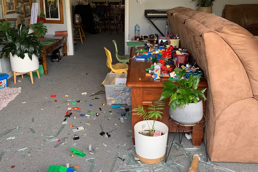 A living room with broken glass after the window has been smashed 