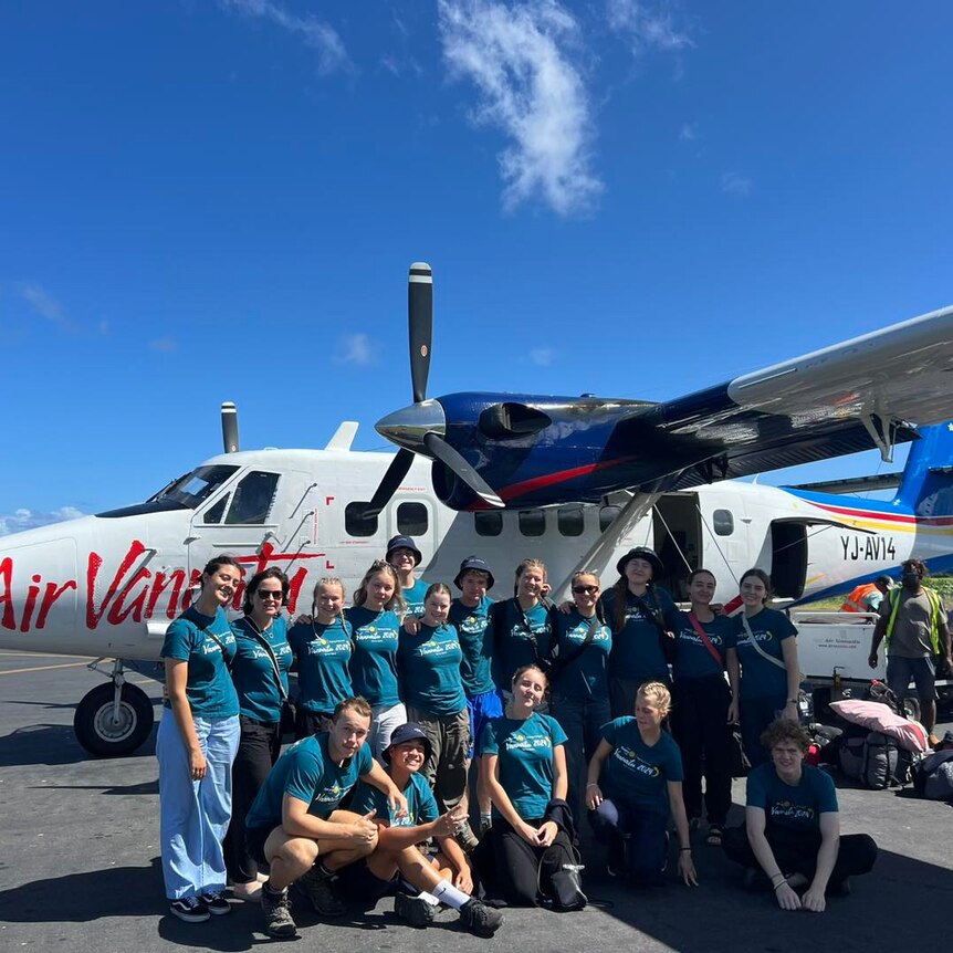 A group of kids standing in front of an air vanuatu plane