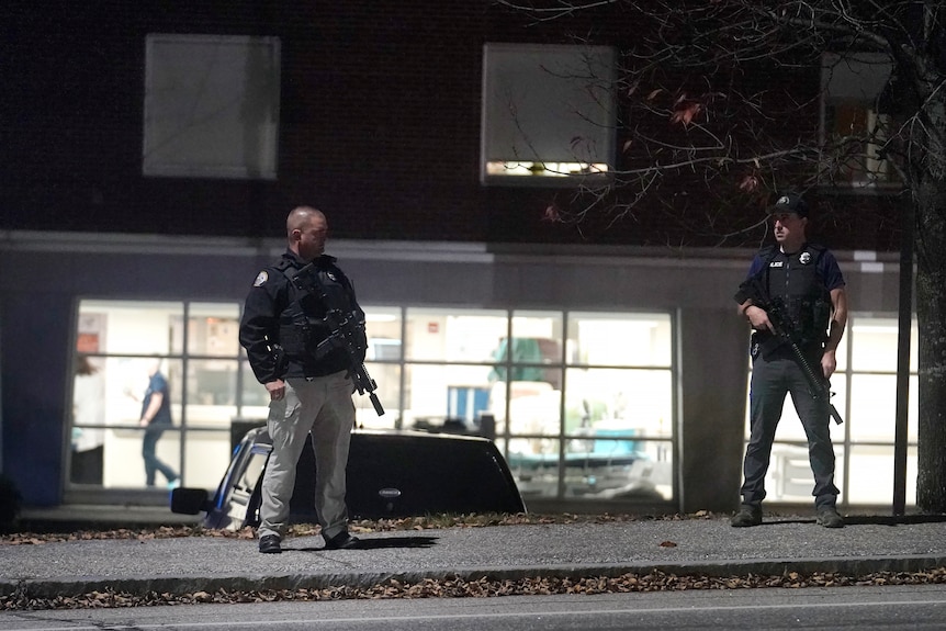 两名男子手持武器站在医院外 