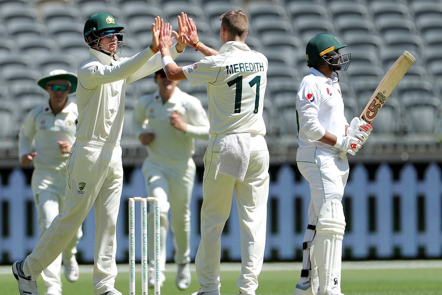 An Australia A bowler gets a high five from a teammate after taking a wicket against Pakistan.