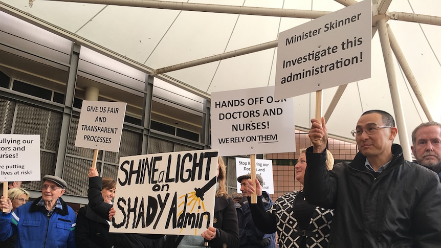People holding signs saying Minister Skinner investigate this administration, Shine a Light on Shady Admin