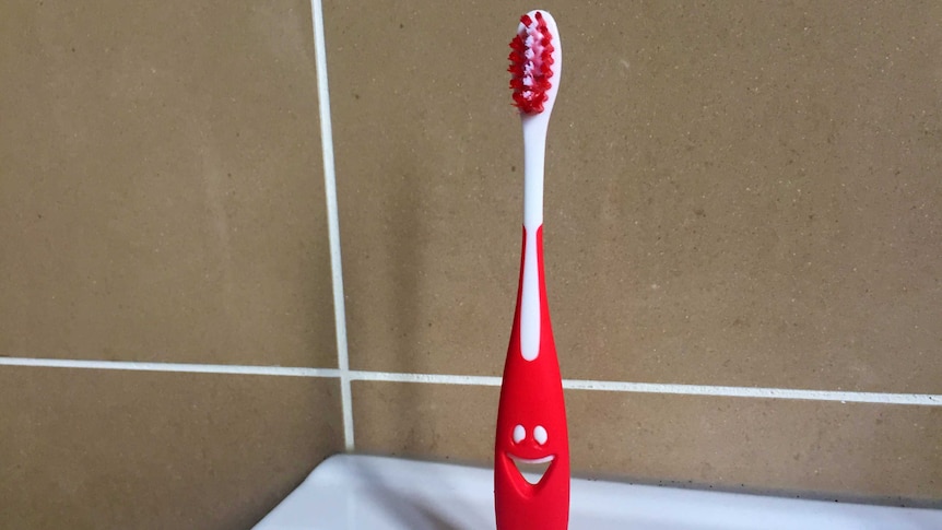 A child's toothbrush stands on a bathroom sink.