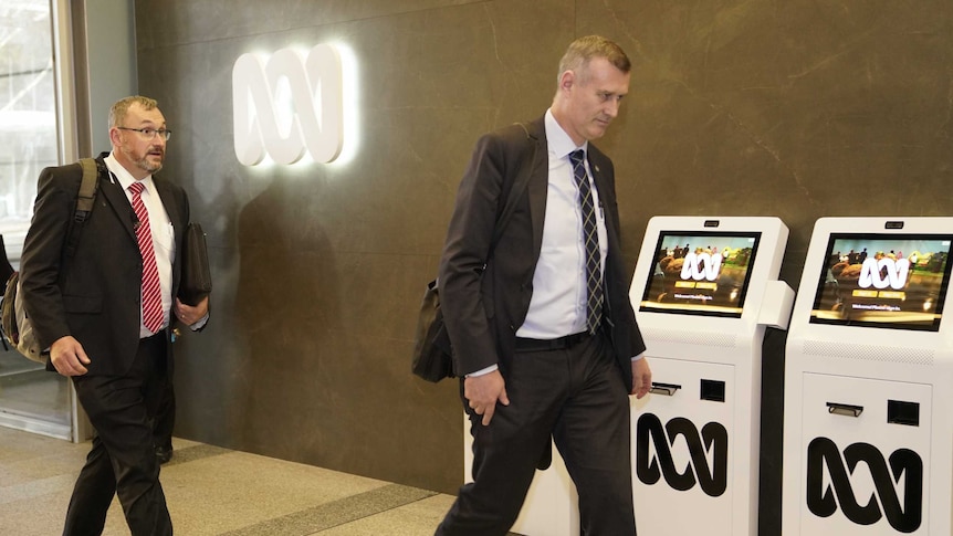 Two men in suits enter the ABC.