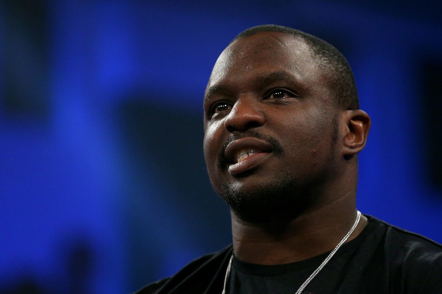 Dillian Whyte smiles against a blue background
