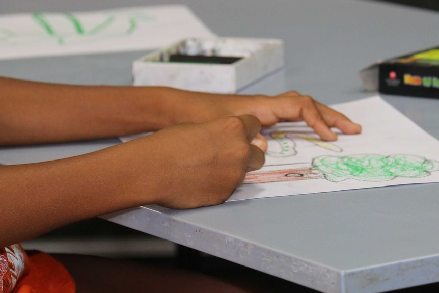 Young Aboriginal student hands on a table.