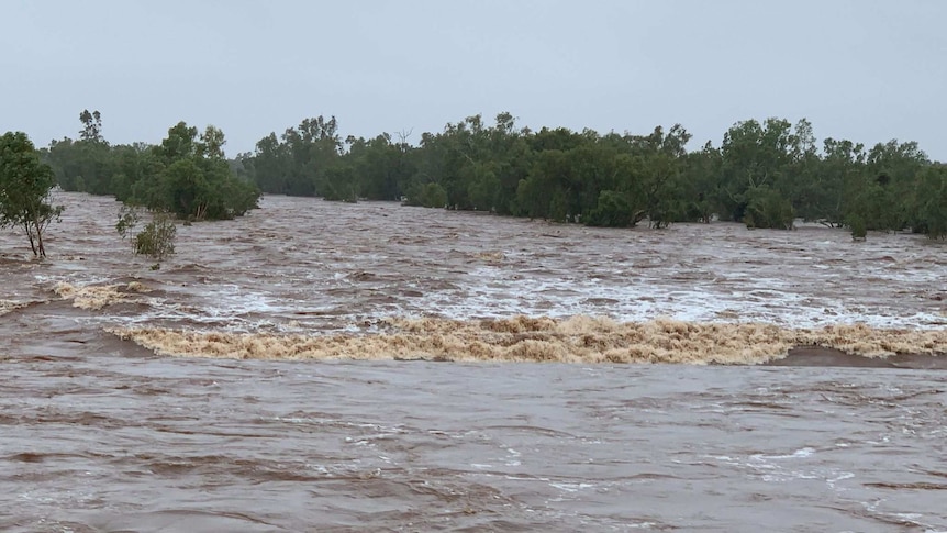 Brown floodwaterw resemble a rapid as it rushes downstream.