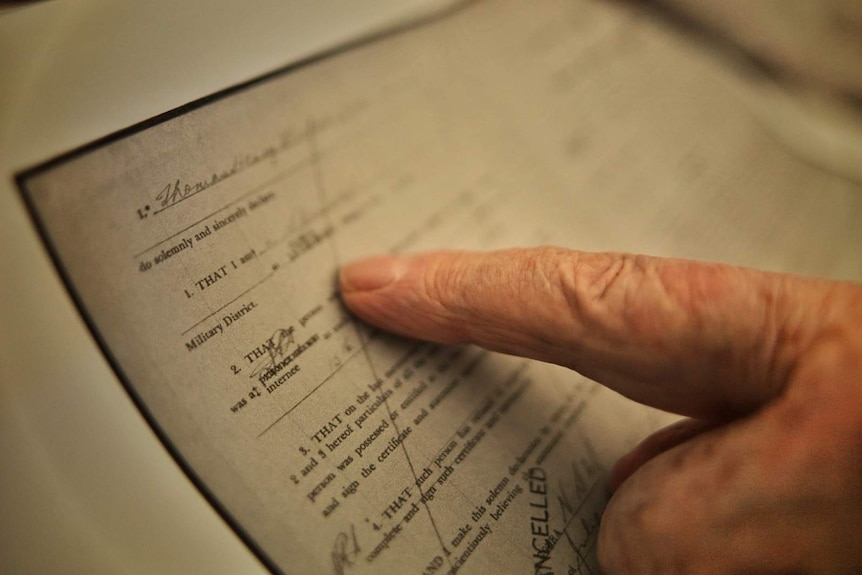 A man's finger pointing at part of a death certificate document.