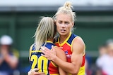 Two Adelaide Crows AFLW players embrace as they celebrate victory.