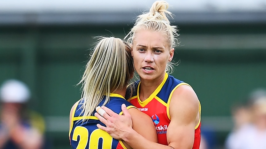 Two Adelaide Crows AFLW players embrace as they celebrate victory.