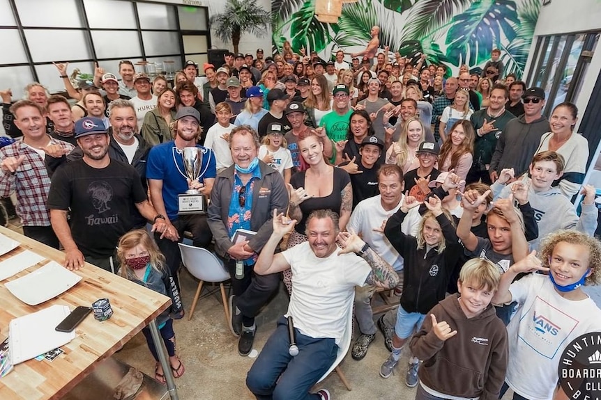 Un gran grupo de personas en una sala llena de gente sonriendo.