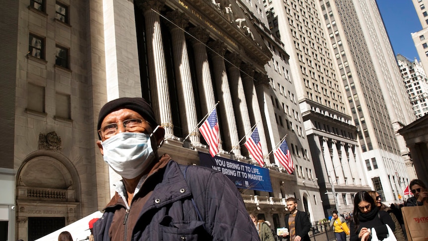 A man wears a mask standing outside the New York Stock Exchange.