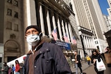 A man wears a mask standing outside the New York Stock Exchange.