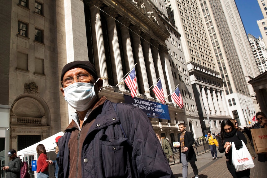 A man wears a mask standing outside the New York Stock Exchange.