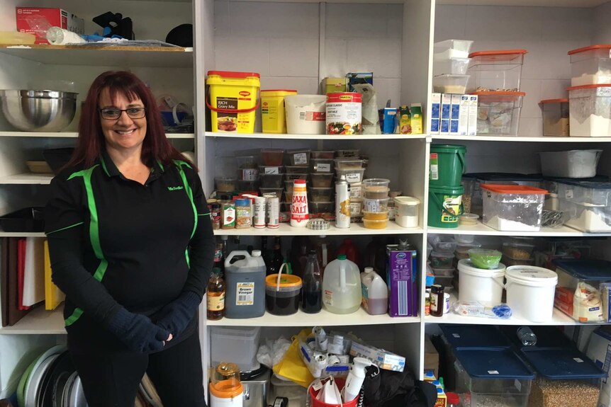 Woman stands in front of kitchen supplies cupboard