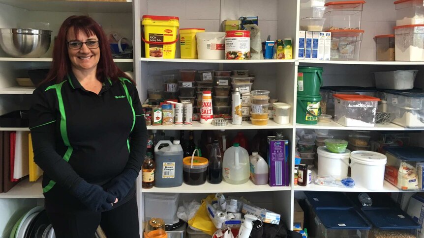 Woman stands in front of kitchen supplies cupboard