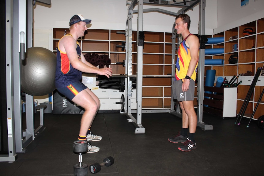 Two men work with a gym exercise ball
