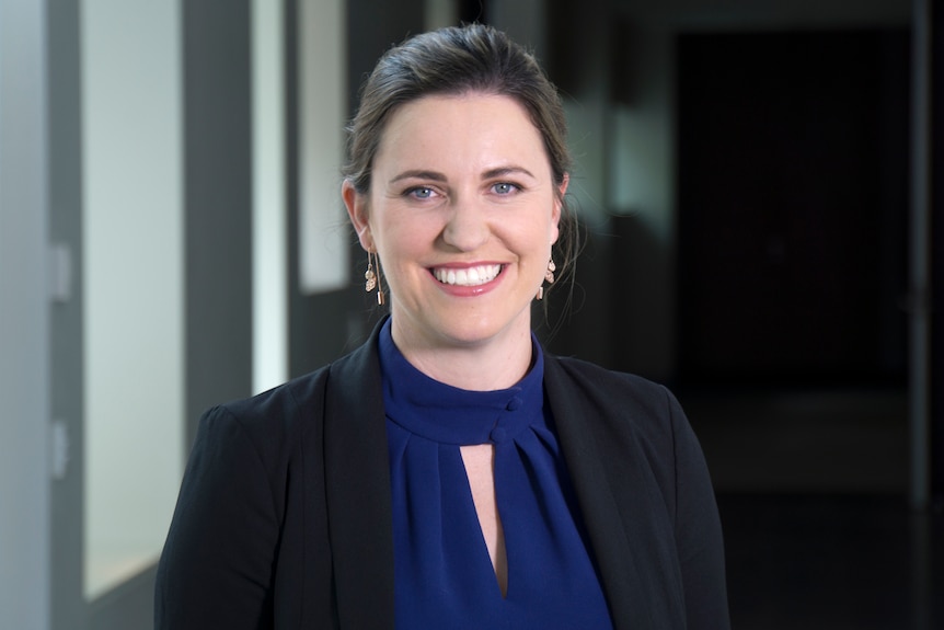 Headshot of a smiling woman wearing earrings and business attire.