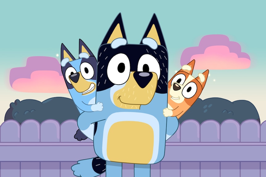 Bandit stands smiling with Bluey and Bingo sitting on his shoulders.