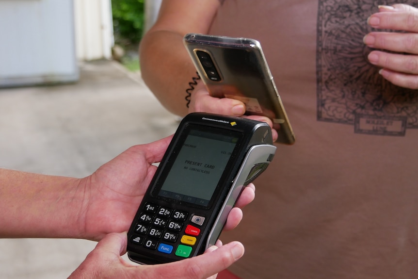 Gros plan sur une machine EFTPOS et quelqu'un essayant de payer avec son téléphone