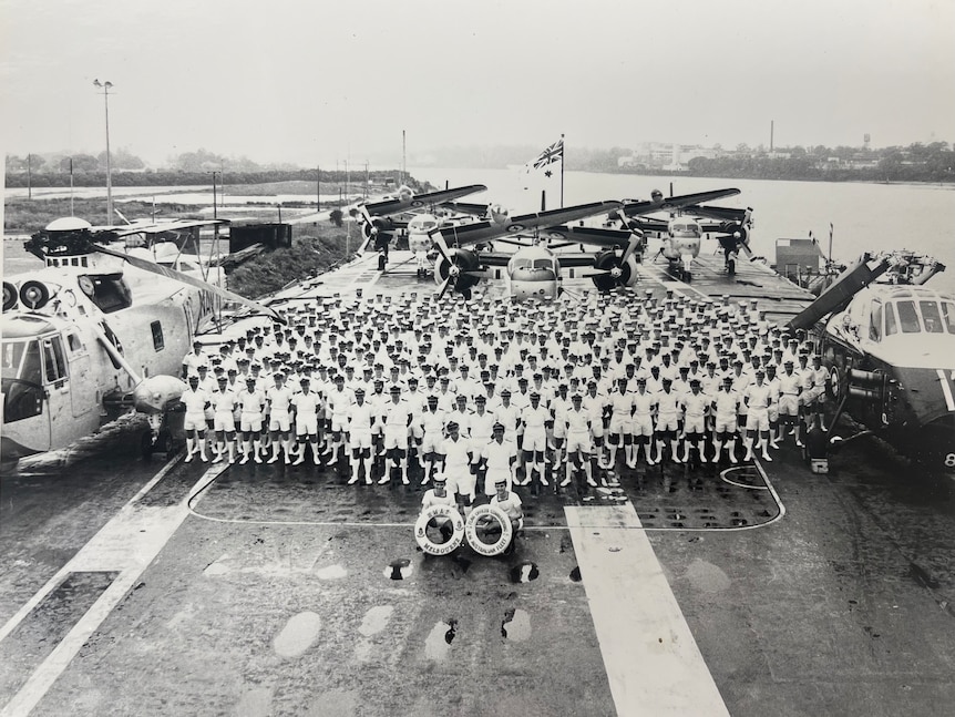 Fred Hooper stands in a group of men on a warship when he was in the Navy