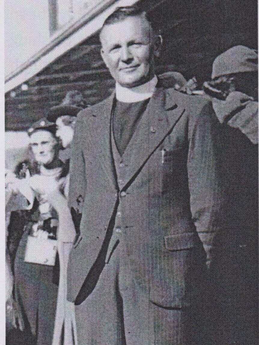 man in paster outfit stands smiling in black and white photo