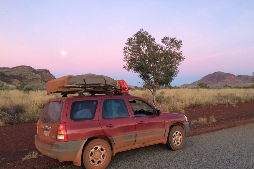 Mattis Mamczek's red four-wheel-drive parked on a red dirt road near Karijini National Park at sunset.