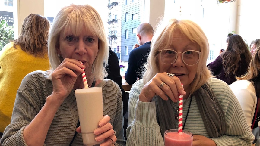 Hazel and Suzanne at a cafe, drinking milkshakes at the table.