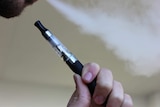 Man inhales vape through through e-cigarette device.
