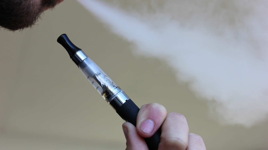 Man inhales vape through through e-cigarette device.