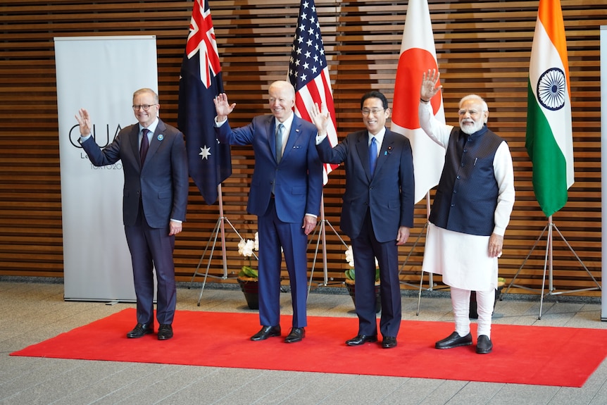 Four men, leaders of their nations, waving for photographers.