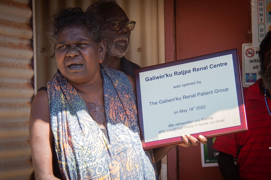 A woman holding a plaque for an opening ceremony.