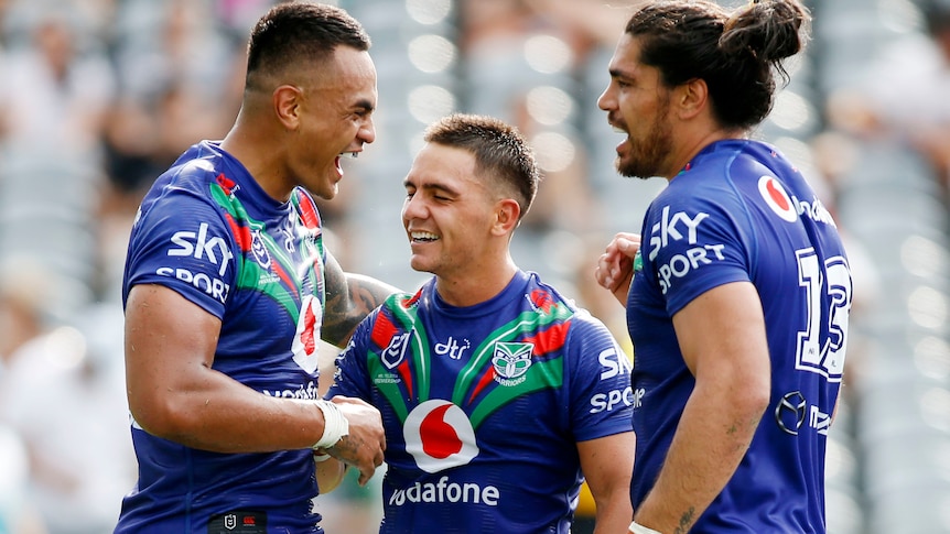Three Warriors' NRL players celebrate a try against the Titans in Gosford.