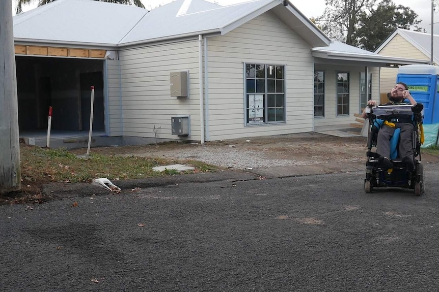 Mr Turner-Thomas sits in his wheelchair outside his almost-built low-set cream home.