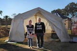 Afghani refugee Shukria Akbari and Syrian refugee Samih Mousa standing outside of a tent.