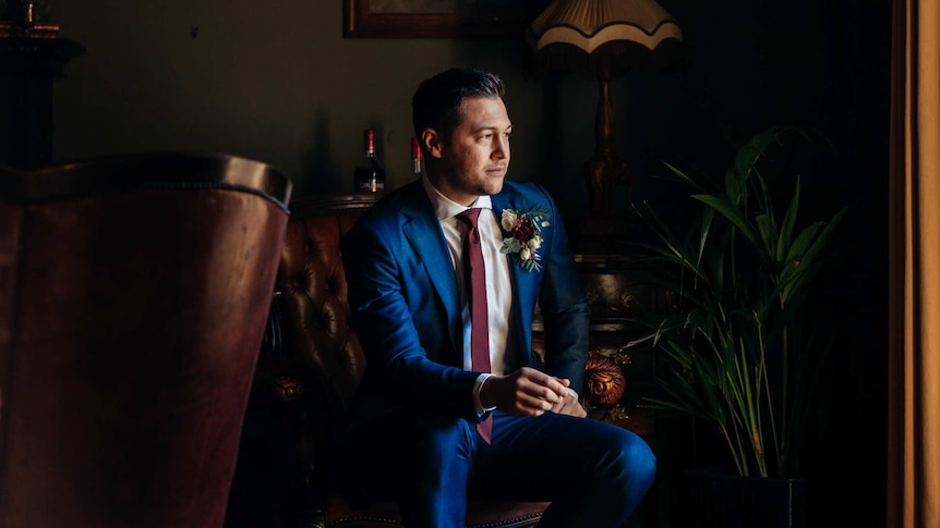 Alexander Hall, wearing a suit, poses for a photo on his wedding day